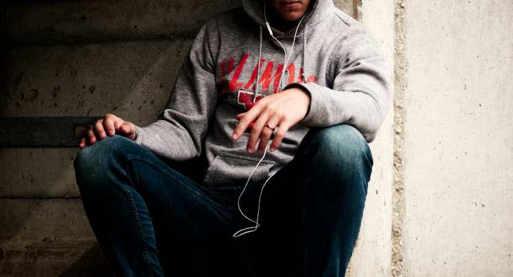 A guy wearing a gray hoodie an dark jeans