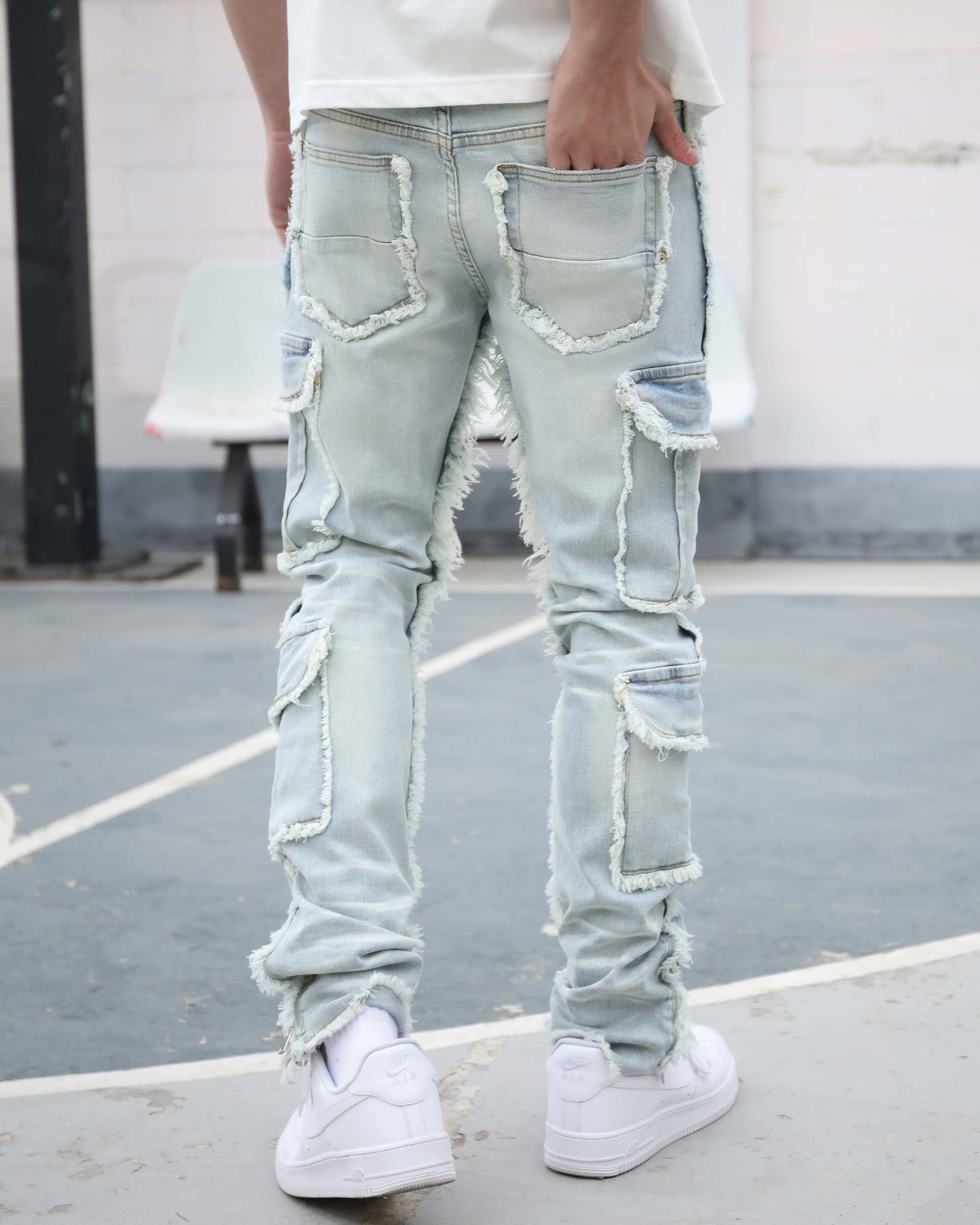 Rear view of LOGEQI's light blue distressed jeans with raw hem inseam and frayed patch cargo pockets.