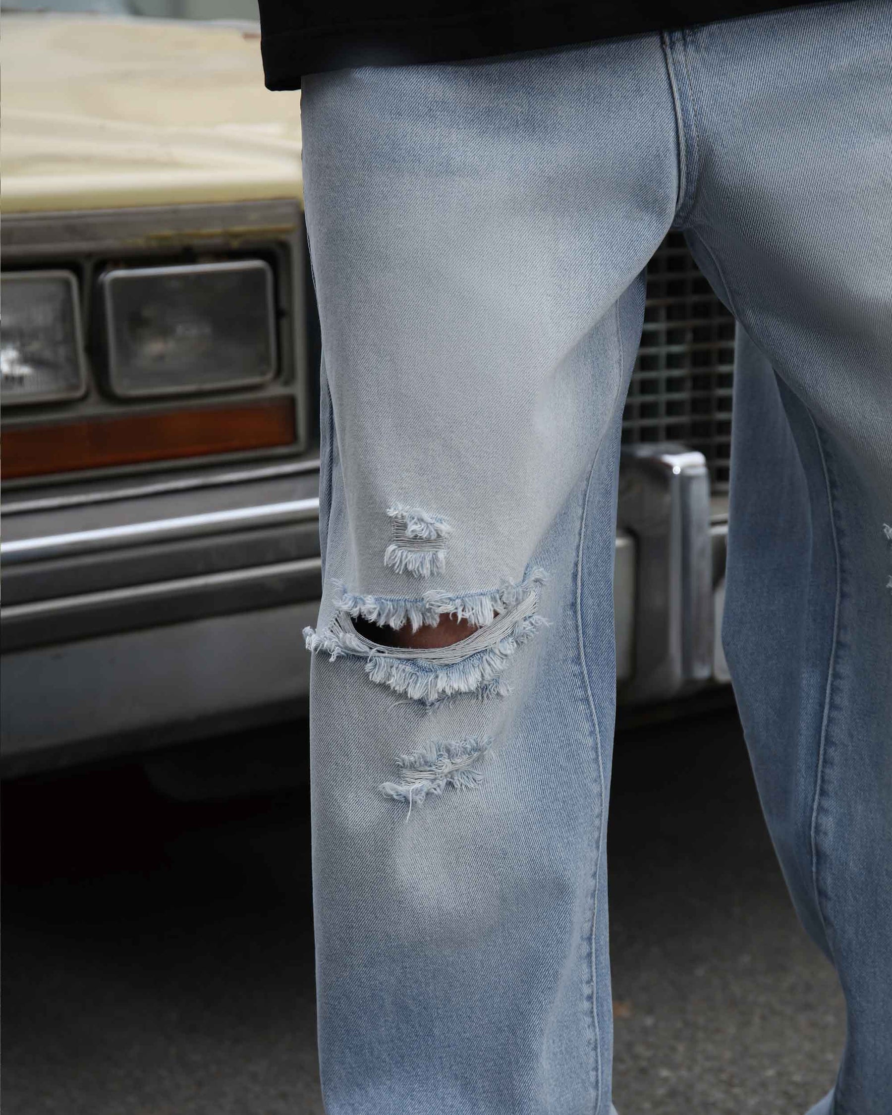 Details of light-wash blue knee-ripped jeans