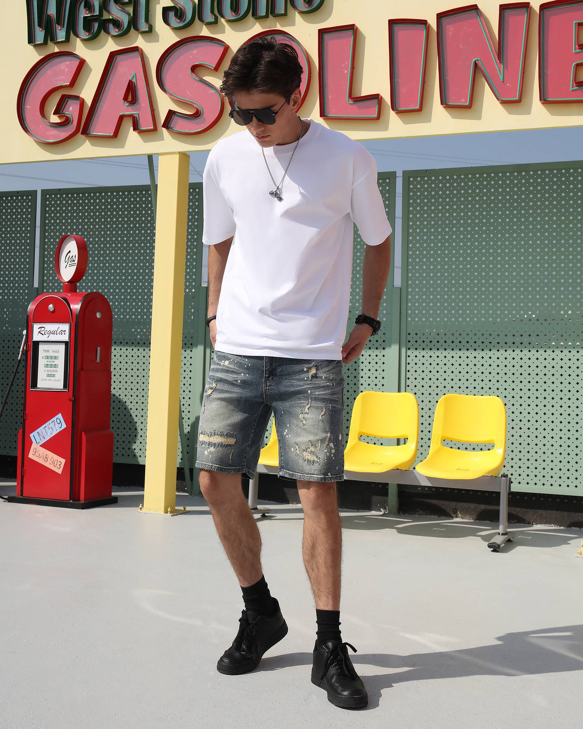 A man wearing LOGEQI's affordable blue denim cargo shorts with a ripped design and white paint splatter, walking on the street.