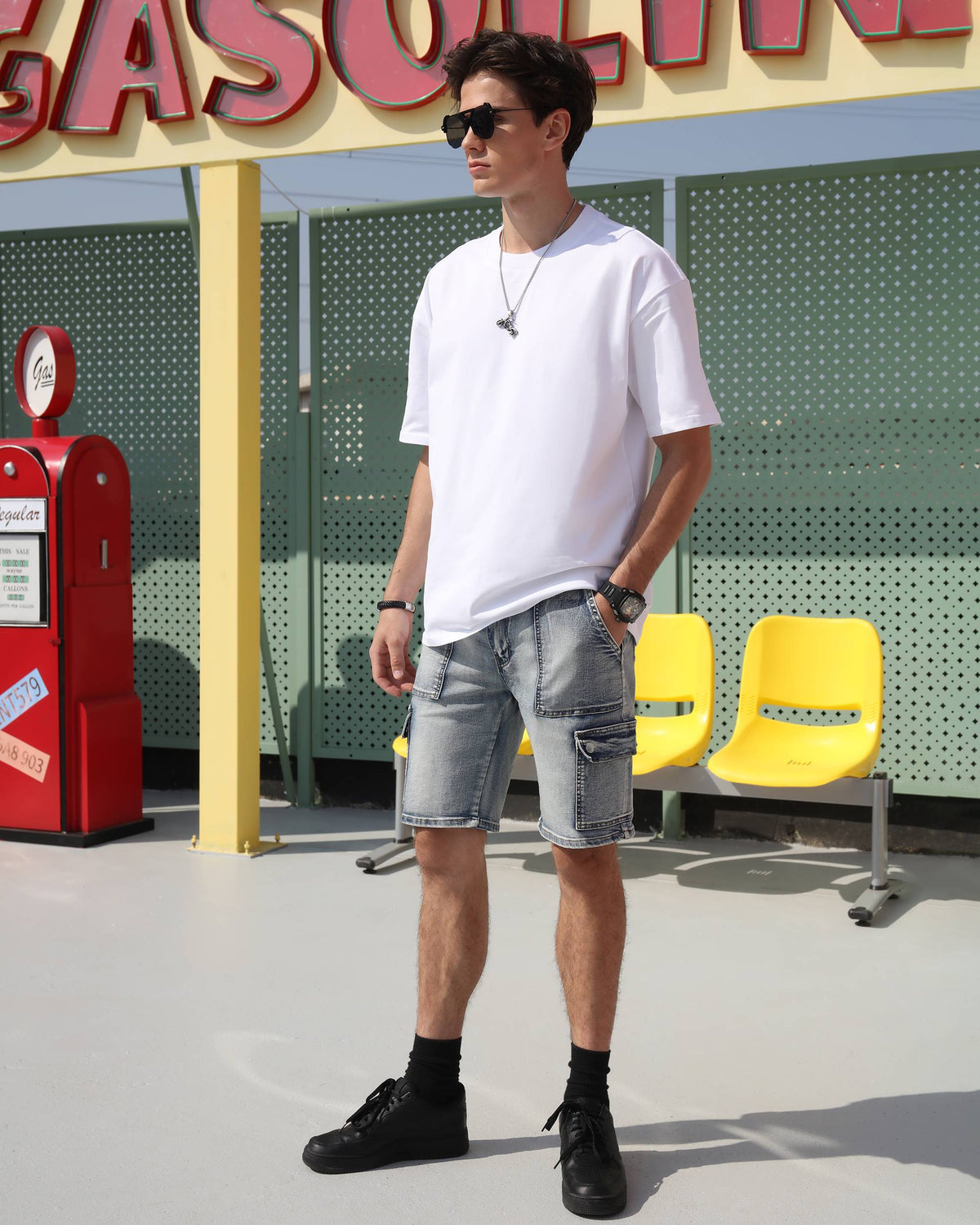 A man showing LOGEQI's blue distressed cargo denim shorts with his one hand in the pockets, wearing sunglasses on the street.