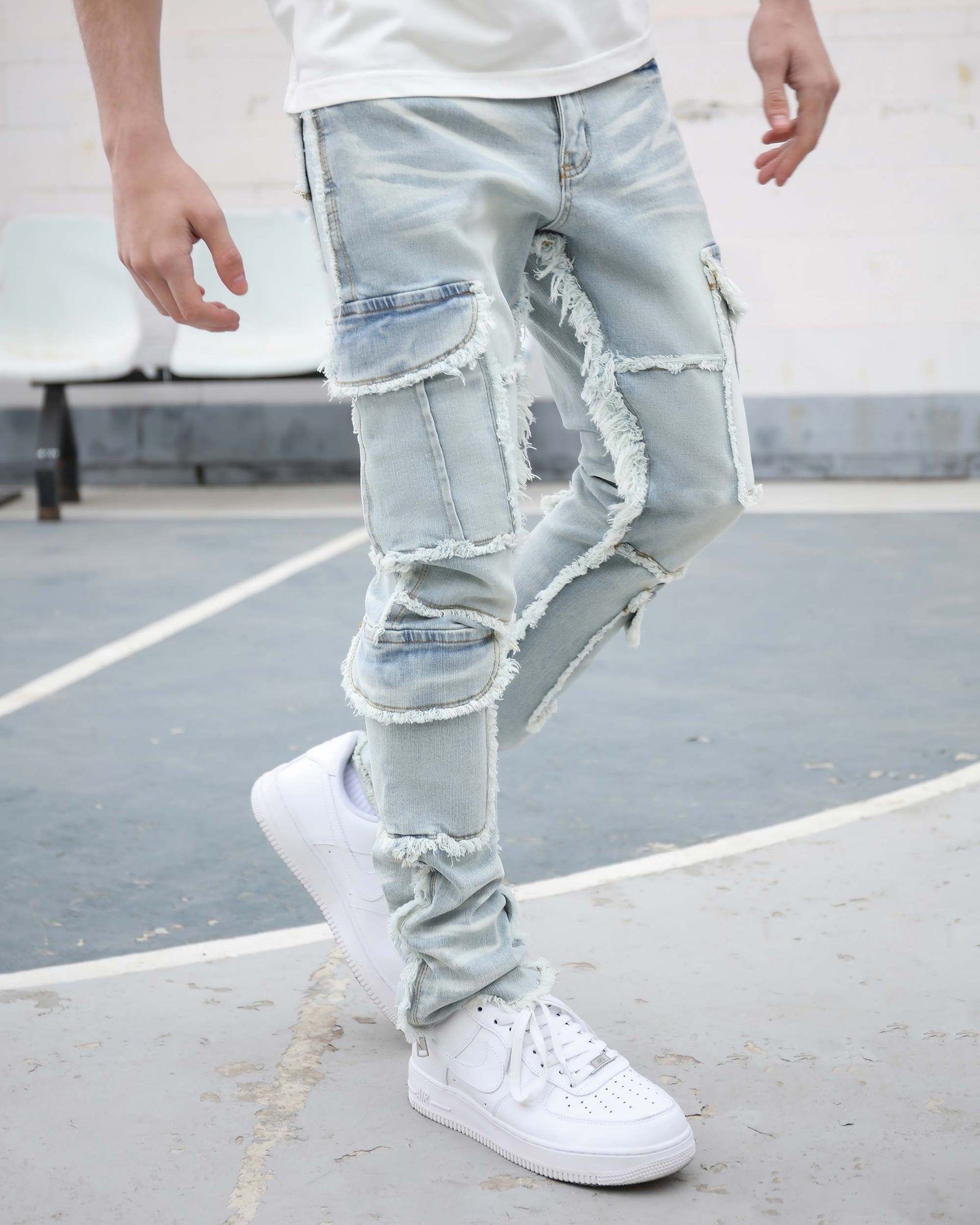 A man wearing LOGEQI's light-wash blue ripped jeans with multiple cargo pockets and raw hems along the inseam