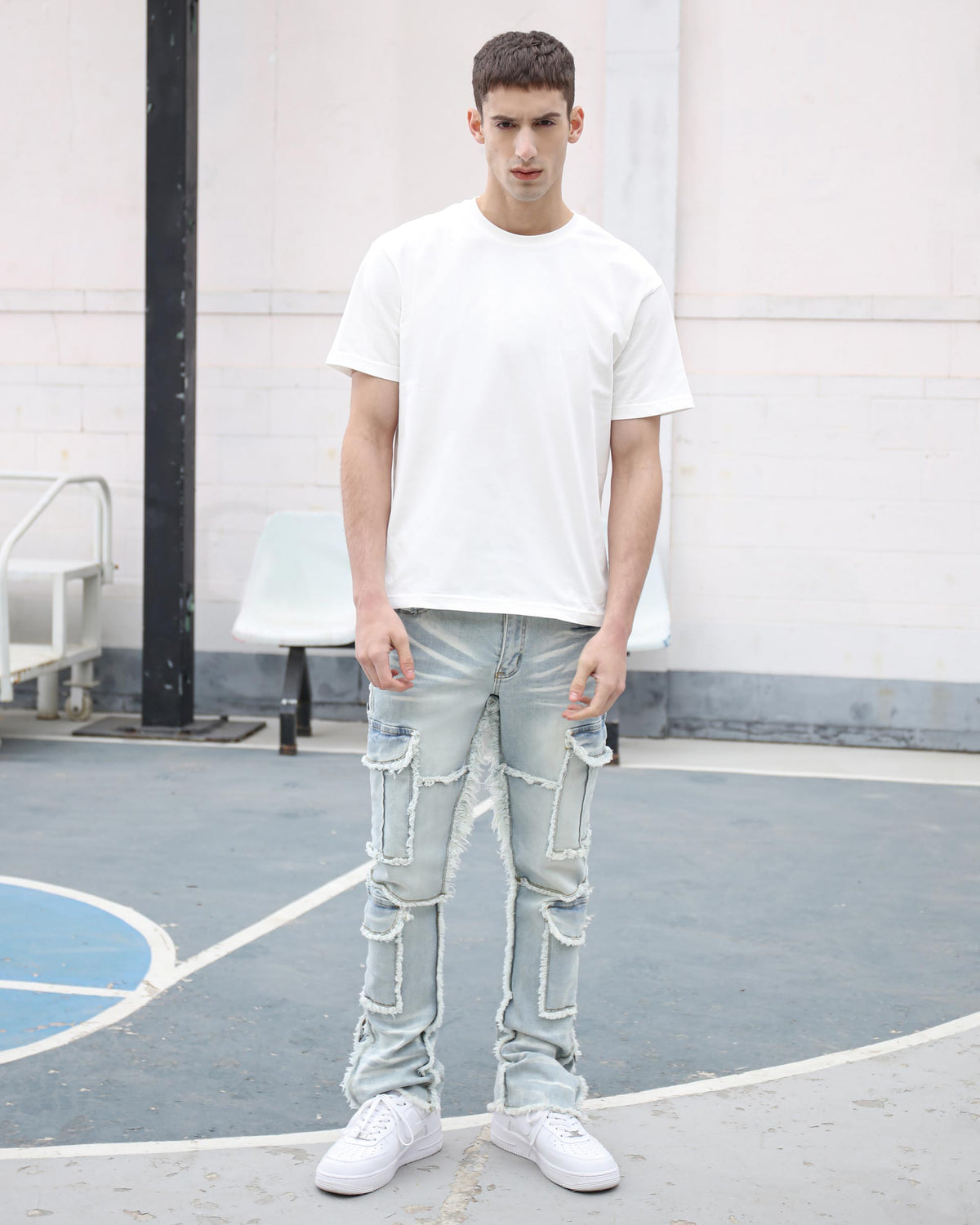 Workwear Flared Jeans with Tassel AccentsA man stands on a basketball court, wearing LOGEQI's light blue distressed denim jeans with frayed patch cargo pockets, a plain white crew-neck tee, and white sneakers — casual streetwear style