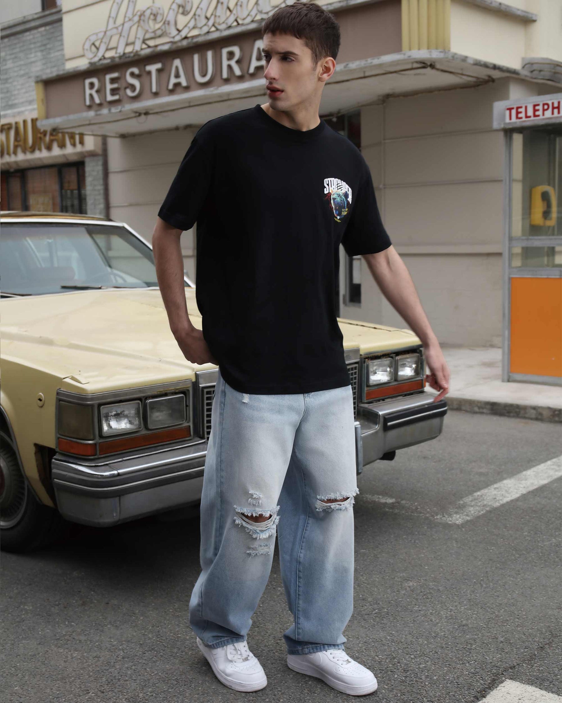 Wearing LOGEQI's blue baggy ripped jeans with a loose black T-shirt, creating a casual and stylish look.