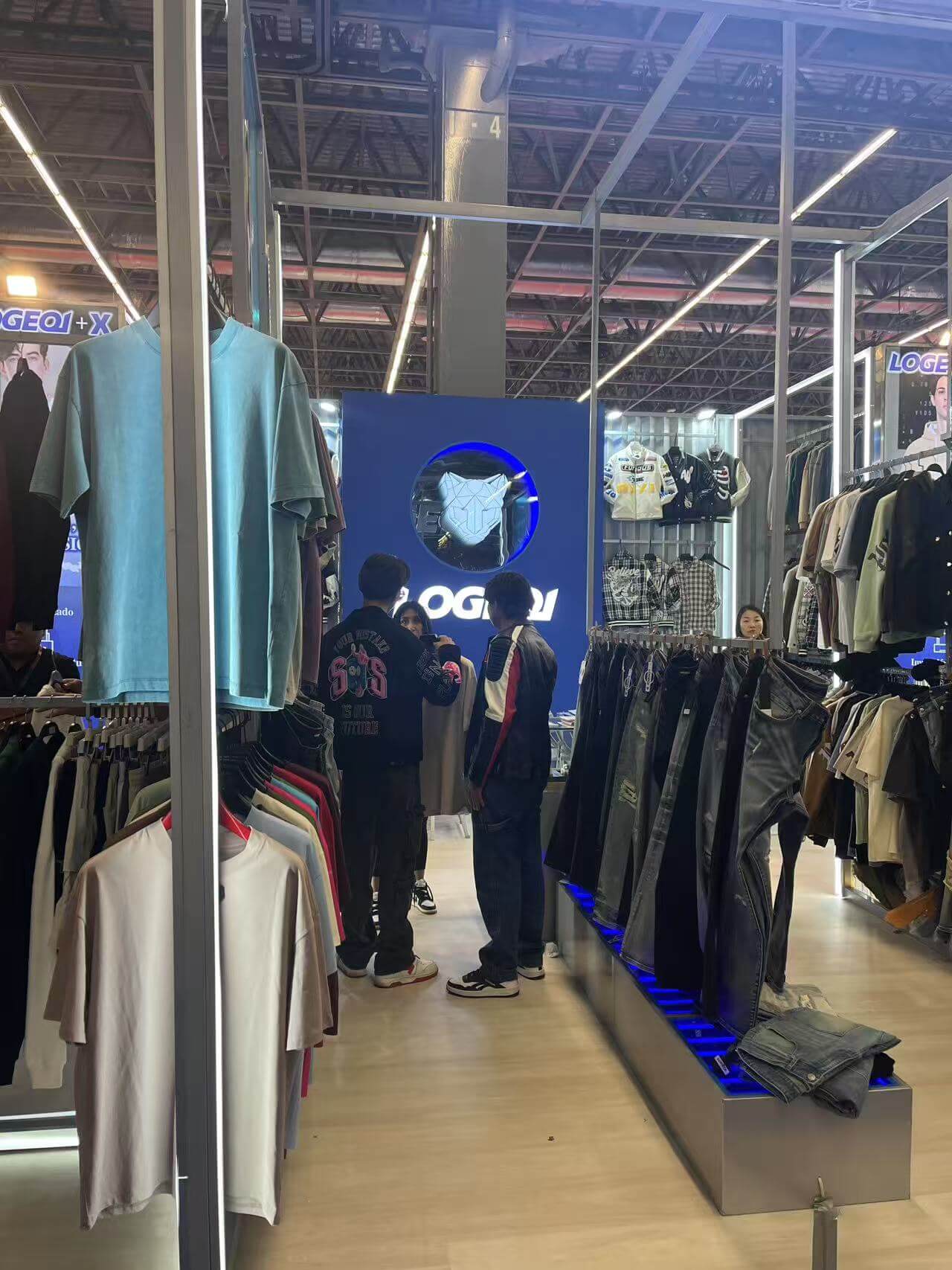 Guys wearing LOGEQI denim jackets talking at the LOGEQI stands at INTERMODA 2025