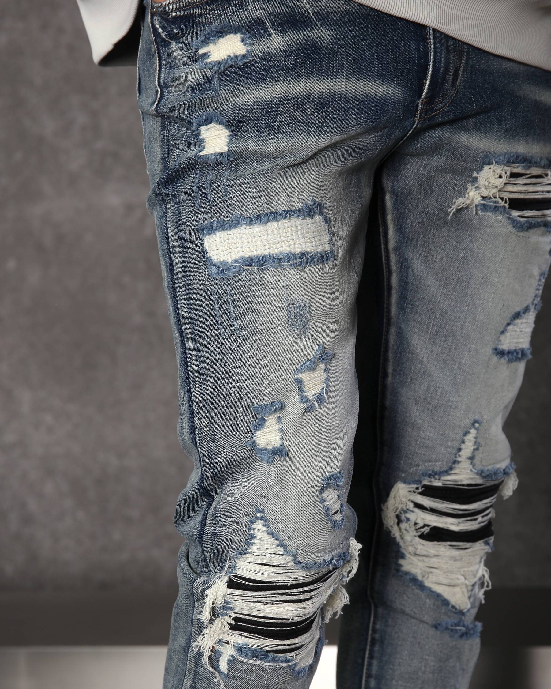 Vaqueros desgastados y rotos azules con parches negros para hombre