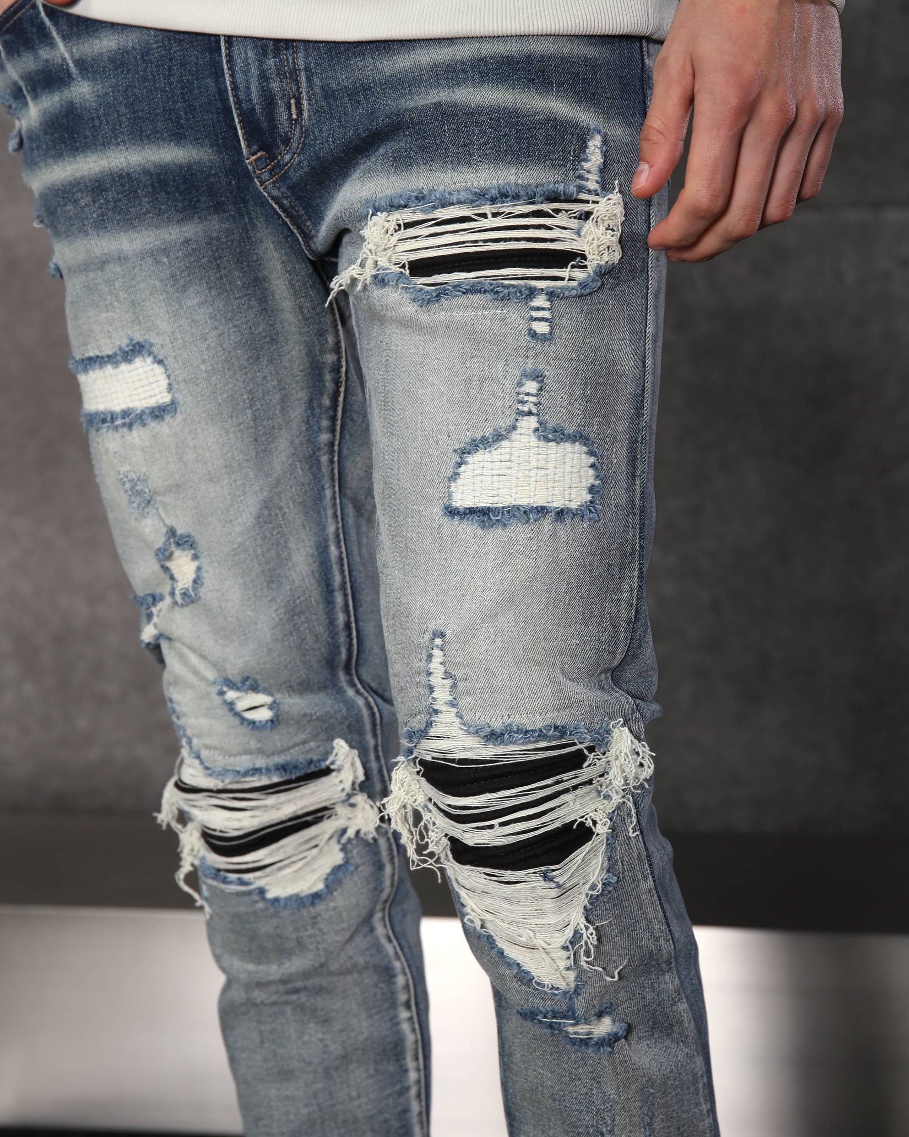 Vaqueros desgastados y rotos azules con parches negros para hombre