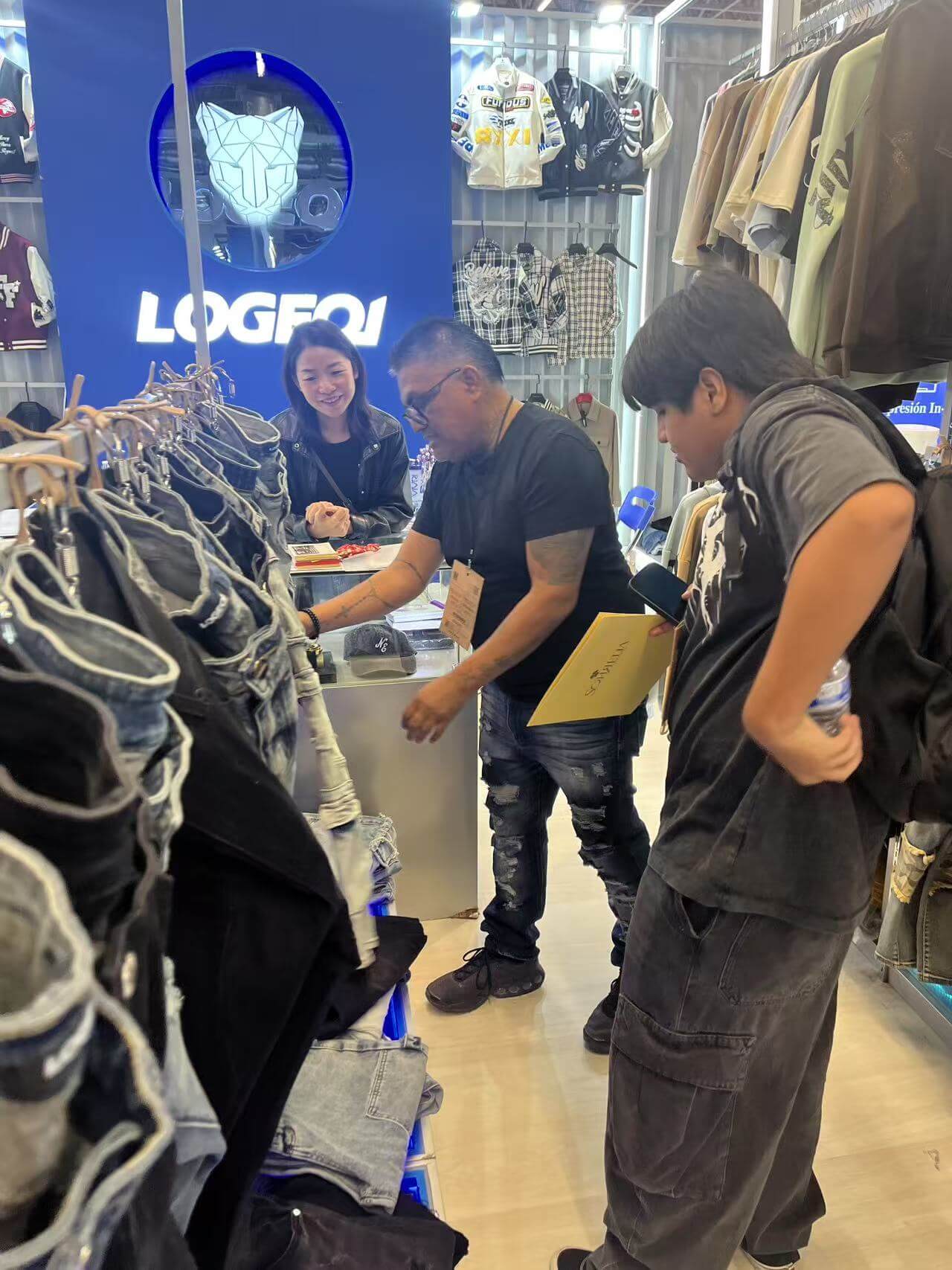 Men carefully checking out LOGEQI's jeans at the INTERMODA 2025 stand