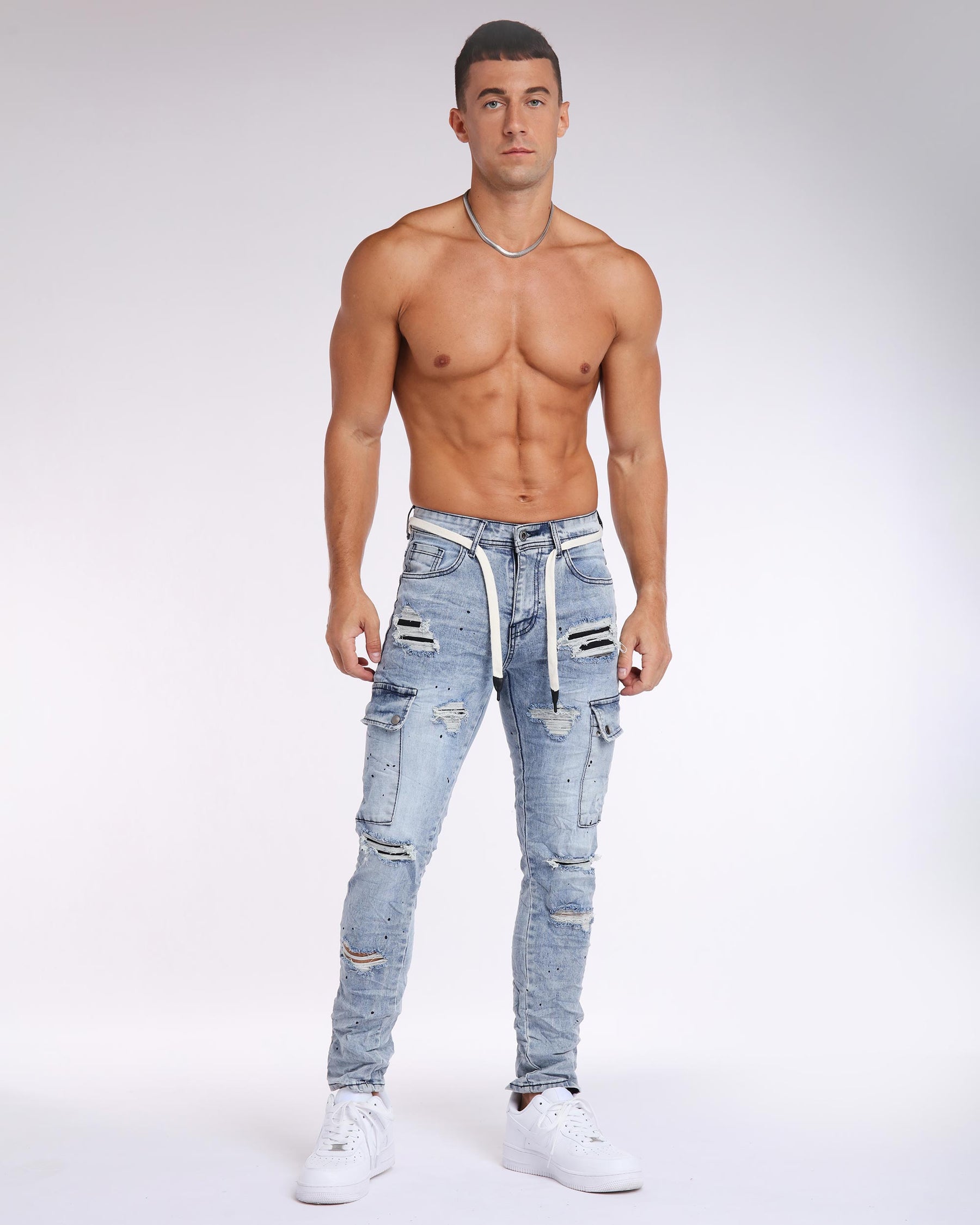 Shirtless man wearing LOGEQI's light wash distressed ripped jeans with black pathes and white sneakers