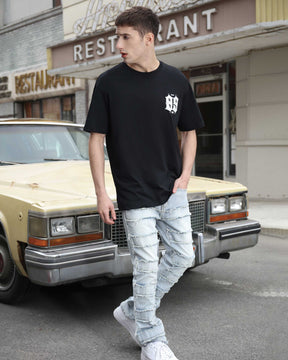 A man wearing light wash blue ripped baggy jeans for men from LOGEQI