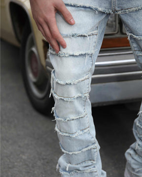 Displaying a close-up shot of LOGEQI's blue ripped and distressed baggy jeans with a layered design