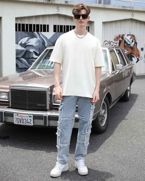 Wearing LOGEQI's street-style men's fringed-edge blue jeans with fringed details, standing on the street and pairing them with sunglasses.