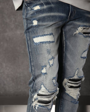 Vaqueros desgastados y rotos azules con parches negros para hombre